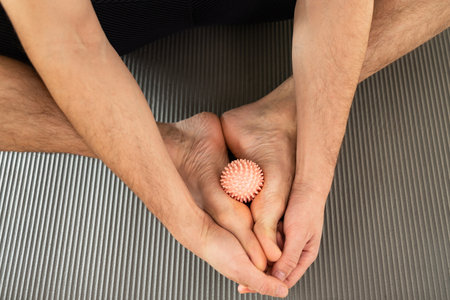 flat feet massaging with a ball. Man using ball with spikes for foot massage doing prevention physical exercise for improving blood circulation at home.の写真素材