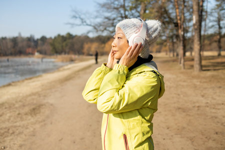 Young woman in sportswear listening to music with headphones on a beach.の写真素材