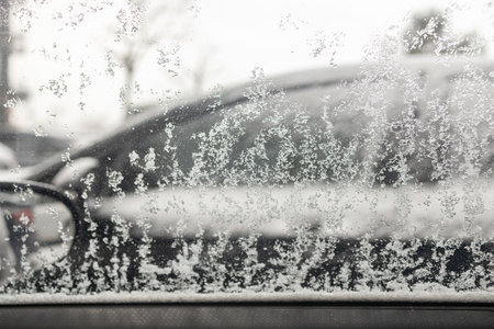 Frozen car parked outdoors, early winter frost. Clumps of Melting Snow Sliding Down Car Side Window.の写真素材