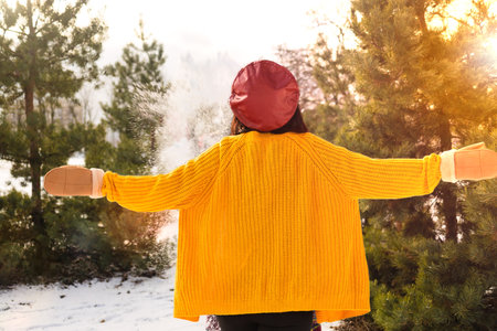 Girl in a yellow sweater and a red hat in the winter forest