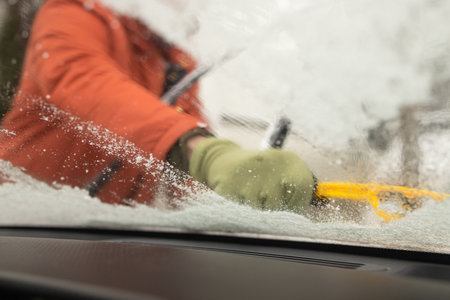 mans'hand deicing front car windshield with scraper. Car at winter. View from inside.の写真素材