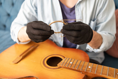Close up on guitar strings in hands of a man guitarist. Changing strings in guitar concept, old used guitar linesの写真素材