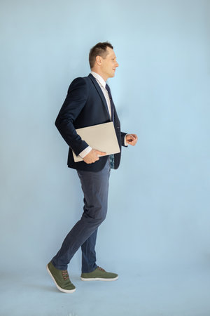Full length portrait of young businessman holding folder and looking away on blue backgroundの写真素材