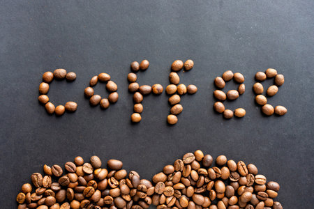 Lettering of English word coffee made of roasted organic beans isolated on black. Typeface for...