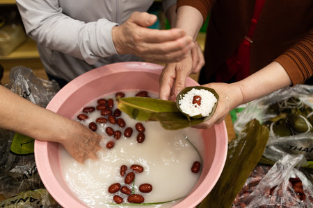 Woman's hand wrapping cake Zongzi or rice dumpling is glutinous rice with sweet or savory fillings wrapped in bamboo or reed leaves.の写真素材
