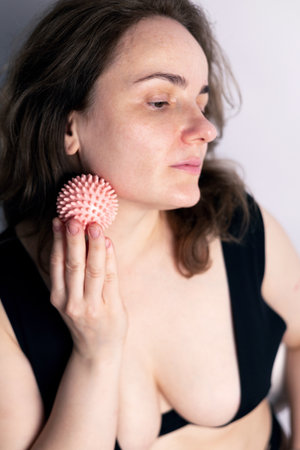 Portrait of a young woman with a massage ball in her handの写真素材