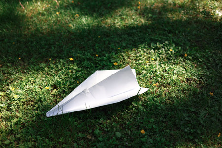 Paper plane on green grass in the park. Close-up.の写真素材
