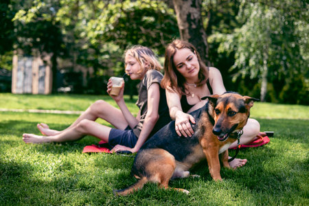 Mom with her child relaxing with dog on grass in the backyard.の写真素材