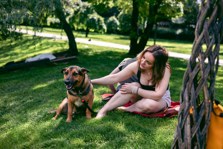 Young woman with her dog on a picnic in the summer park.