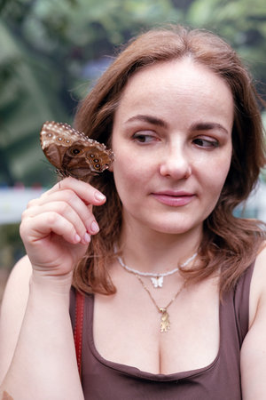 Portrait of a young brunette woman with butterfly in garden.の写真素材