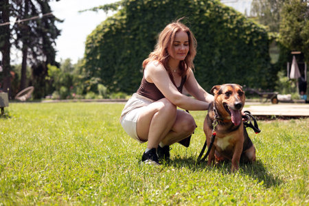 Beautiful young woman with her dog in the park in summer.の写真素材