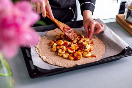 Close up of woman's hands decorating banana tart, cooks delicious pie with fresh berries and jamの写真素材