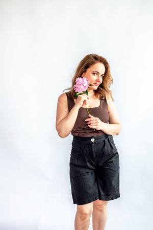 Young woman holding a pink rose in her hand. White background.の写真素材