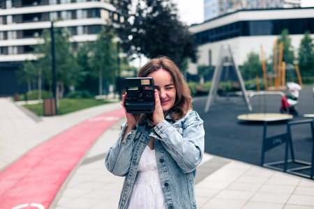 Young beautiful girl in a denim jacket with a camera in the cityの写真素材