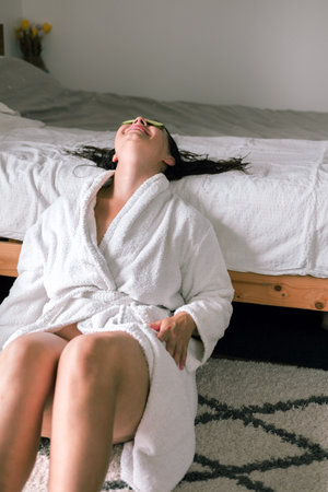 Young woman in a bathrobe relaxing on the bed at home.の写真素材