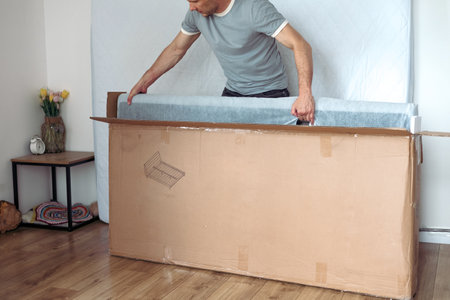 Man furniture maker assembles bed. Process production interior items. Guy makes furniture for bedroom. Worker assembles bed frame. Sleeping bed productionの写真素材
