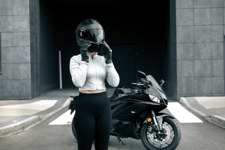 Biker Woman with Helmet posing on street. Cool competitive female motorcyclist wearing protective gearの写真素材