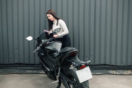 woman washing sport motobike. Girl cleaning a black motorcycle outdoor.の写真素材