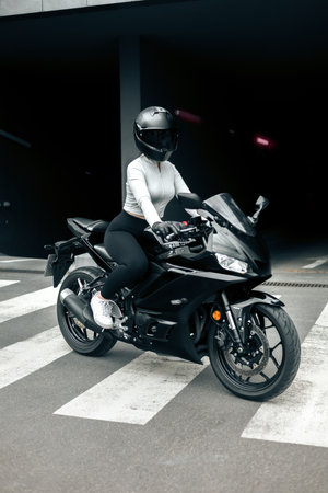Biker in helmet and sportswear sitting on a motorcycle.