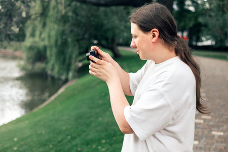 Teen boy holding camera and taking photo outdoor. Hobby or career. Beginner photographer with...