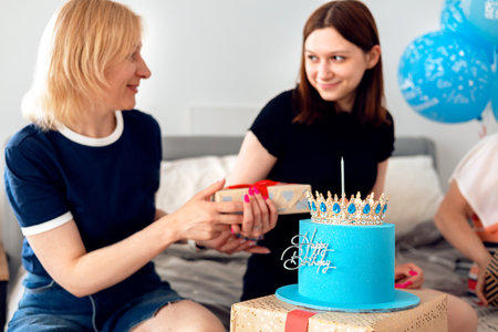 Mother and daughter celebrating birthday with cake and gift box. Family holiday conceptの写真素材