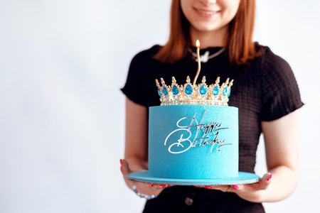 Birthday cake with a crown in the hands of a girl on a white backgroundの写真素材