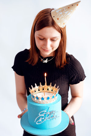 teenage girl holding birthday cake decorated with a golden crown and candles. Happy Birthday concept.の写真素材
