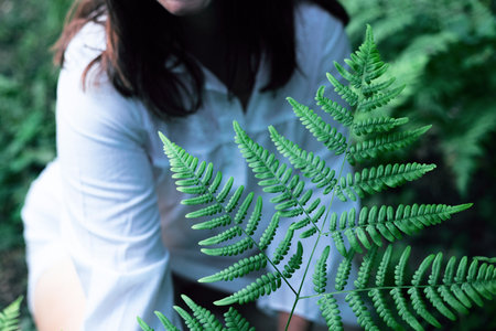 hipster woman with fern leaf covering. girl with natural herb. romantic moment.