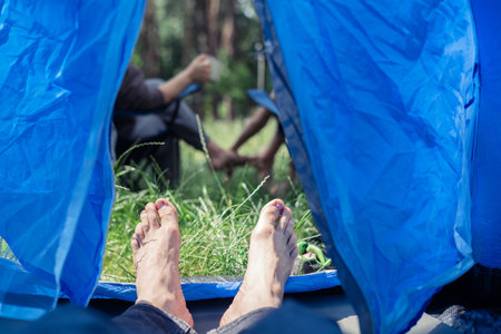 camping, travel, tourism, hike and people concept - close up of male legs in tentの写真素材