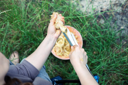 Top view of female hands holding fork and knife while eating pasta outdoorsの写真素材
