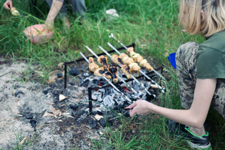 Young woman cooking sausages on the fire in the forest.の写真素材