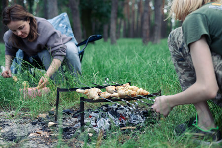 Happy family with teen boy on a picnic near the tent and grill a barbecue in a pine forest. Camping, recreation, hiking.の写真素材