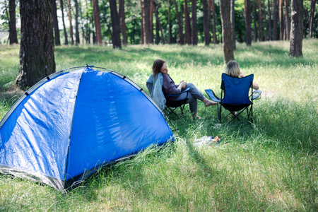 Happy family with teen boy on a picnic near the tent and grill a barbecue in a pine forest. Camping, recreation, hiking.の写真素材