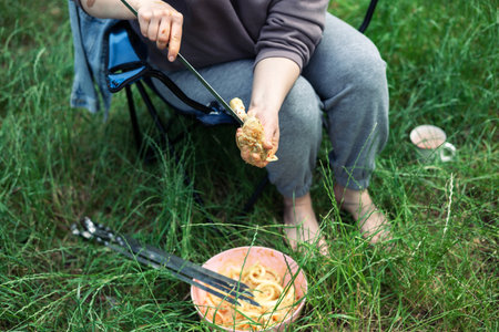 Happy family with teen boy on a picnic near the tent and grill a barbecue in a pine forest. Camping, recreation, hiking.の写真素材