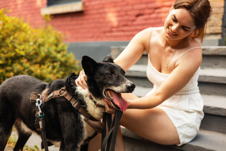 Beautiful young woman in a white dress with a dog on the streetの写真素材