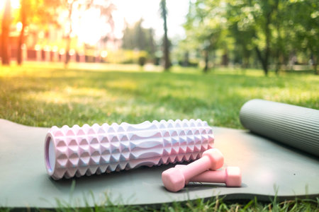 yoga mat, foam roller and dumbbells in the sunset sun, in soft focus, close-up. Outdoors fitness concept.の写真素材