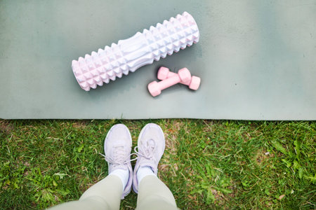 Female legs in sneakers and dumbbells on green grass, top viewの写真素材