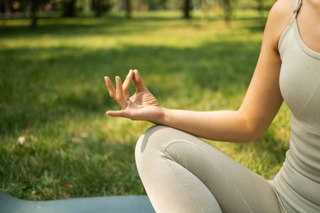 Close-up of young woman meditating in lotus position in park