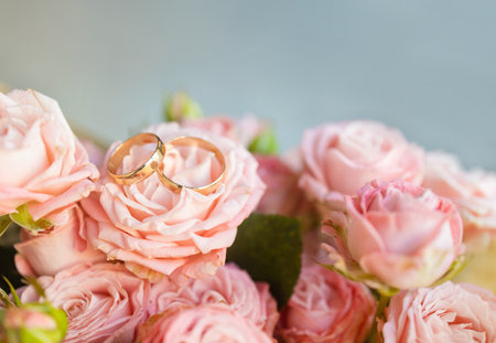 Wedding concept. Golden rings on the background of a bouquet of pink roses.の写真素材