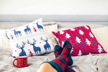 Legs of young woman in warm socks on the bed with Christmas decorations.の写真素材