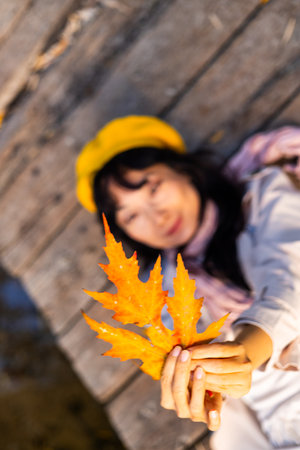 Beautiful asian woman holding autumn maple leaf in her hand.