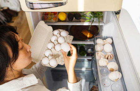 Female hand taking white egg from a fridgeの写真素材