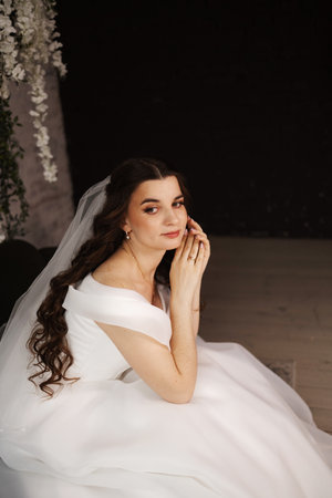 Portrait of a beautiful bride with makeup and hairstyle in a white dressの写真素材