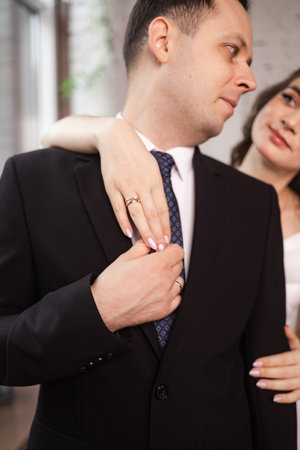 man putting on tie in front of womanの写真素材
