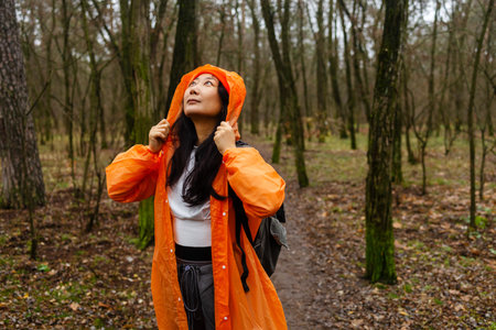 Portrait of a young woman in an orange raincoat in the forest.の写真素材