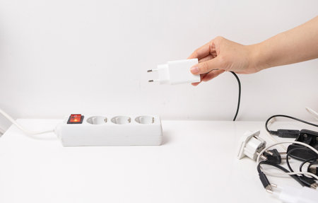 Woman's hand plugging a power strip on a white background.