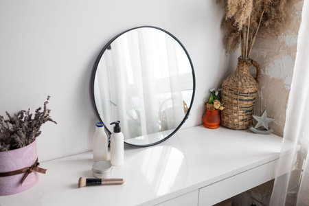 Mirror and cosmetic products on the table in a modern bathroom.