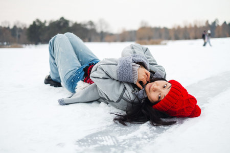Portrait of a beautiful young Asian woman laying down on a frozen snow lake playing games during a...
