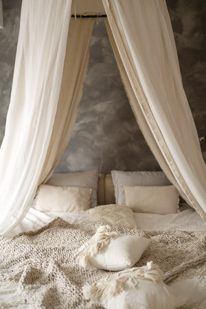 Still life concept. Vertical photo of cozy apartment in boho style interior with comfort bedroom, plaid, pillows and blanket on bed.の写真素材