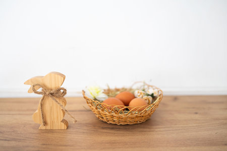 Wooden Easter bunny and eggs on wooden table over white wall background